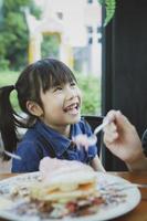 lycka ansikte av asiatiska barn med söt dessert på bordets förgrund foto