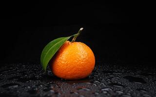 mogen saftig mandarin på en svart bakgrund med vatten droppar. foto