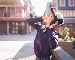 glad ung asiatisk kvinna som lyssnar på musik med hörlurar på gatan foto