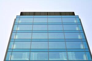 glas byggnad med transparent Fasad av de byggnad och blå himmel. strukturell glas vägg reflekterande blå himmel. abstrakt modern arkitektur fragment. samtida arkitektonisk bakgrund. foto