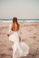 modell i boho stil i en vit lång klänning och silver- Smycken på de strand. henne hår är flätad, och där är många armband på henne vapen. foto