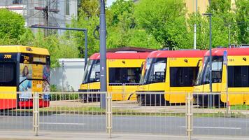 Warszawa, polen. 28 april 2024. modern röd och gul spårvagnar på gata. offentlig transport. foto