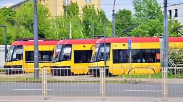 Warszawa, polen. 28 april 2024. modern röd och gul spårvagnar på gata. offentlig transport. foto
