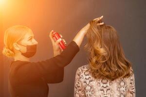 kvinnor salong frisyr. frisör användningar hårspray på klientens hår i salong, porträtt av två skön kvinnor foto