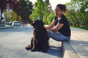 Lycklig ung kvinna njuter de utomhus med henne sällskapsdjur hund. Söt kvinna gående henne svart cockerspaniel spaniel på koppel foto