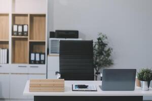 eleganta arbetsyta med skrivbordet dator, kontor förnödenheter, krukväxt och böcker på kontor. skrivbord arbete begrepp. foto