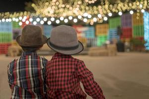 två pojkar sitter tillsammans i park nattevenemang foto