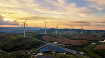 solnedgång landskap vindkraftverk gård ren grön energi för elektrisk detta är flygfoto som flyger från drönare foto