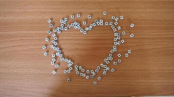 hjärta från alfabet vit pärlor block med brev i hjärta slumpmässig brev runt om topp se trä- bakgrund foto