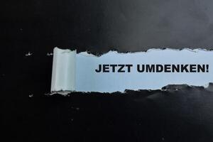 begrepp av jetzt umdenken i språk Tyskland text skriven i trasig papper. foto