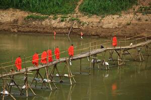 buddist munkar korsning bambu bro över de mekong flod, luang prabang, laos foto