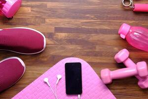 smart telefon med hörlur hantel, sko och övning matta golv foto