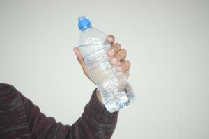en person är gripande en plast flaska med deras fingrar och tumme foto
