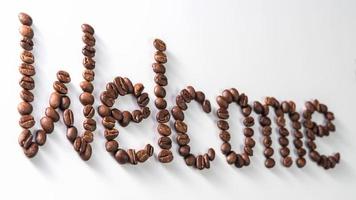 text gjord av kaffebönor, isolerad på vitt. sms:a ordet välkommen gjord av kaffebönor. font foto