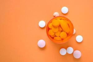 vit piller och orange behållare på Färg bakgrund foto