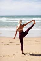 kaukasisk blond kvinna utövar yoga på stranden foto