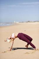 kaukasisk blond kvinna utövar yoga på stranden foto