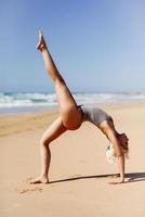 kaukasisk blond kvinna utövar yoga på stranden foto