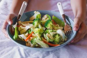blandad grönsaksmat på skålen i handen, nyttiga blandade grönsaker. foto