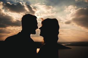 silhuetter av par som kysser, bruden och brudgummen som håller händerna på en bakgrund av berg och floder foto