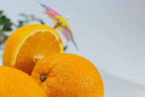 tre apelsiner under ett matlagningsparaply, en apelsin halverad foto