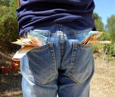 50 och 20 euro sedlar fastnar ut av de fickor av en blå jeans foto