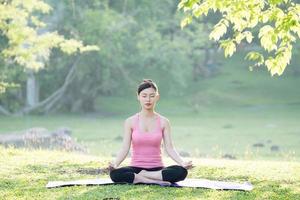 ung vacker asiatisk kvinna som utövar yoga foto