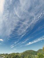 blå himmel med kemtrails från luft plan, konturer, natur bakgrund, spiral formad moln foto