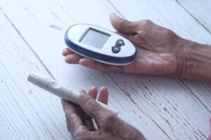 äldre kvinnor diabetiker mäter glukosnivån hemma foto