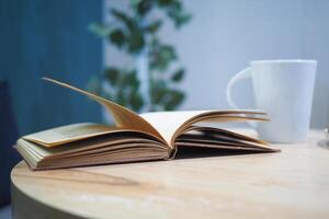 en öppen bok och en kaffe kopp på en Kafé tabell foto