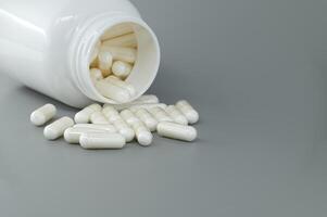 vit medicin flaska spill piller över grå bakgrund foto