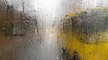 regn på bakrutan på en bil på hösten. inifrån vägen med rörliga bilar i staden genom fönstret från bilen med regndroppar. köra bil i bakrutans synfält. foto