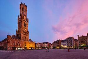 klocktorn torn och stora markt fyrkant i Brugge, belgien på skymning i skymning foto