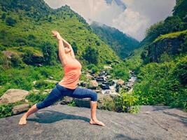 kvinna håller på med ashtanga vinyasa yoga asana virabhadrasana 1 krigare foto