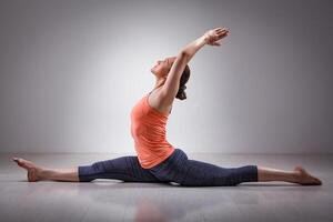 sportig passa kvinna håller på med yoga asana hanumanasana foto