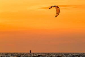 lekar kite kiteboarder kitesurfer drakar silhuett i de hav på solnedgång foto