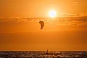 lekar kite kiteboarder kitesurfer drakar silhuett i de hav på solnedgång foto