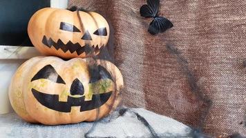 pumpa med ett läskigt ansikte på ett träbord. interiören av huset är dekorerad med pumpor och spindelnät för semestern av halloween.