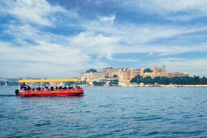 turister båt på sjö pichola med stad palats i bakgrund. udaipur, Indien foto