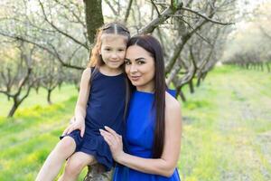 en Lycklig familj. mor och dotter resten i de parkera i klänningar foto