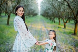 en Lycklig familj. mor och dotter resten i de parkera i klänningar foto