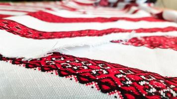 ukrainsk folkhandbroderi. broderad prydnad med röd-svarta trådar på vitt tyg. broderad prydnad i svart och röd tråd. etniska ukrainska folkbroderier på vitt tyg. foto