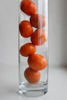 sju saftig mandarin frukt i en kolumn i en lång glas vas foto