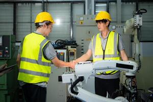 ingenjör och arbetstagare skakning händer medan arbetssätt på industriell maskin i fabrik foto