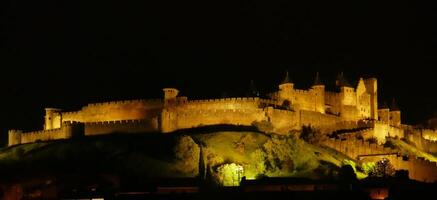 natt lampor på de vallar och slott torn av medeltida carcassonne foto