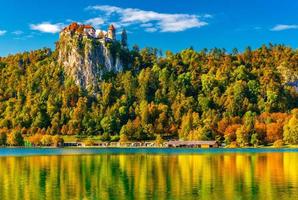 pittoresk utsikt över sjön blödde under hösten, Slovenien. vackert landskap med färgglada träd på kullarna som reflekteras i vattnet foto