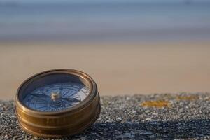 kompass på sten avsats utsikt hav sand och himmel i bakgrund. bakgrund bild foto