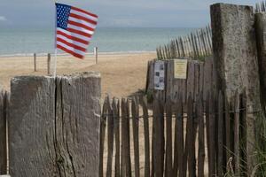 utah strand i Normandie, Frankrike. mitten räckvidd se USA flagga på trä hav staket. foto