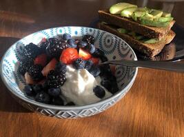 avokado rostat bröd och skål av bär och yogart frukost foto