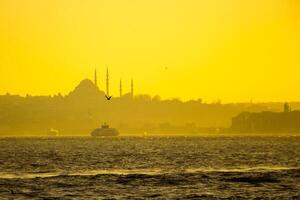 istanbul se på solnedgång. suleymaniye moské och färja på de bosphorus foto